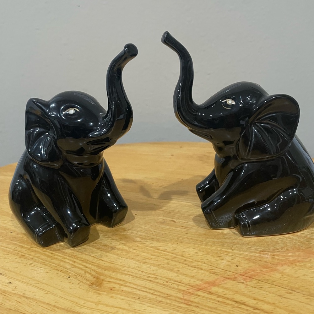 Two ceramic black sitting elephants with truck up